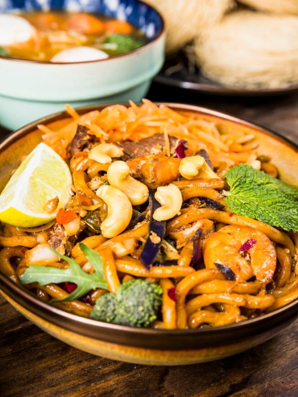 tasty-thai-udon-noodles-with-beef-broccoli-mint-nuts-lemon-bowl-wooden-table_23-2148093292